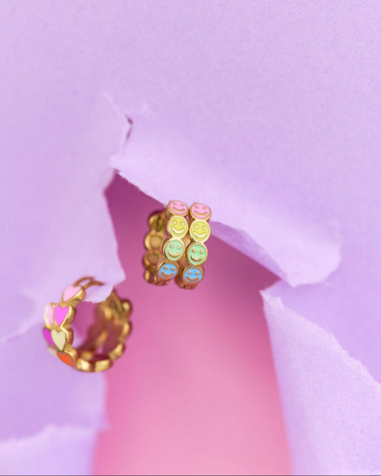 Colorful hoop earrings on a pink and purple background
