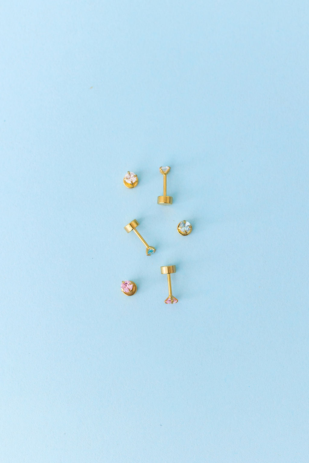 Gold earrings on a light blue background