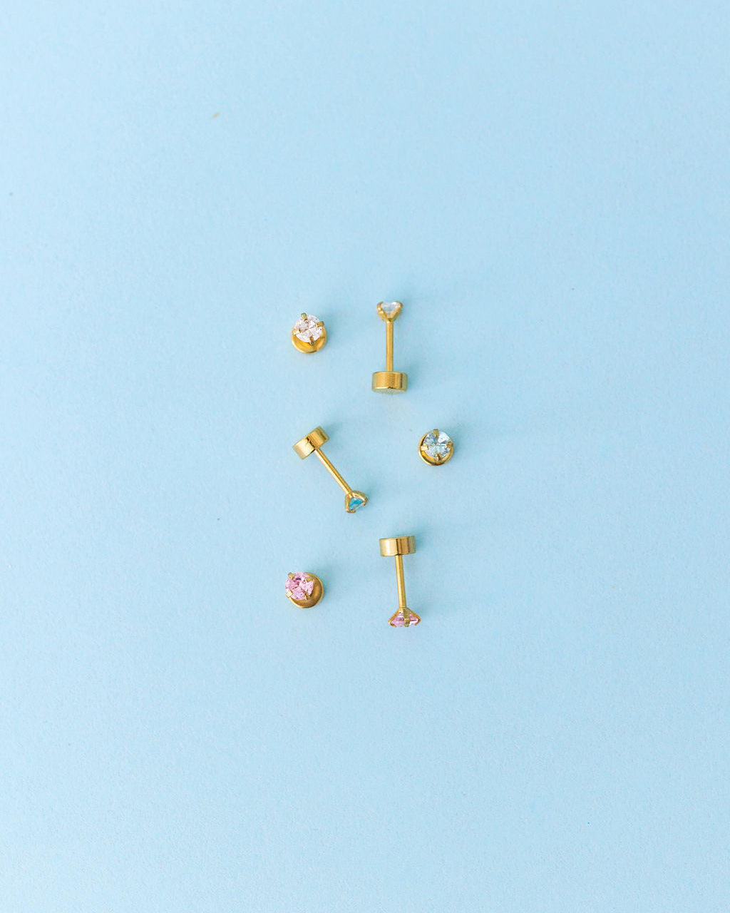 Gold earrings on a light blue background