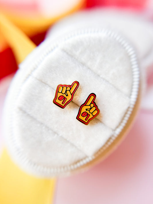 Handmade earrings with red and yellow designs on a white surface with a colorful background