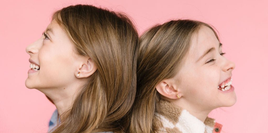Desert Peach girls wearing earrings and laughing with pink background