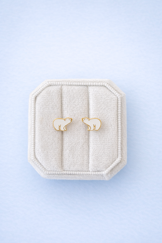Gold bear-shaped earrings in a decorative box on a light blue background