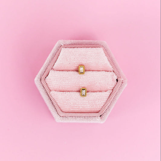 Hexagonal pink jewelry tray with two gold rings on a pink background