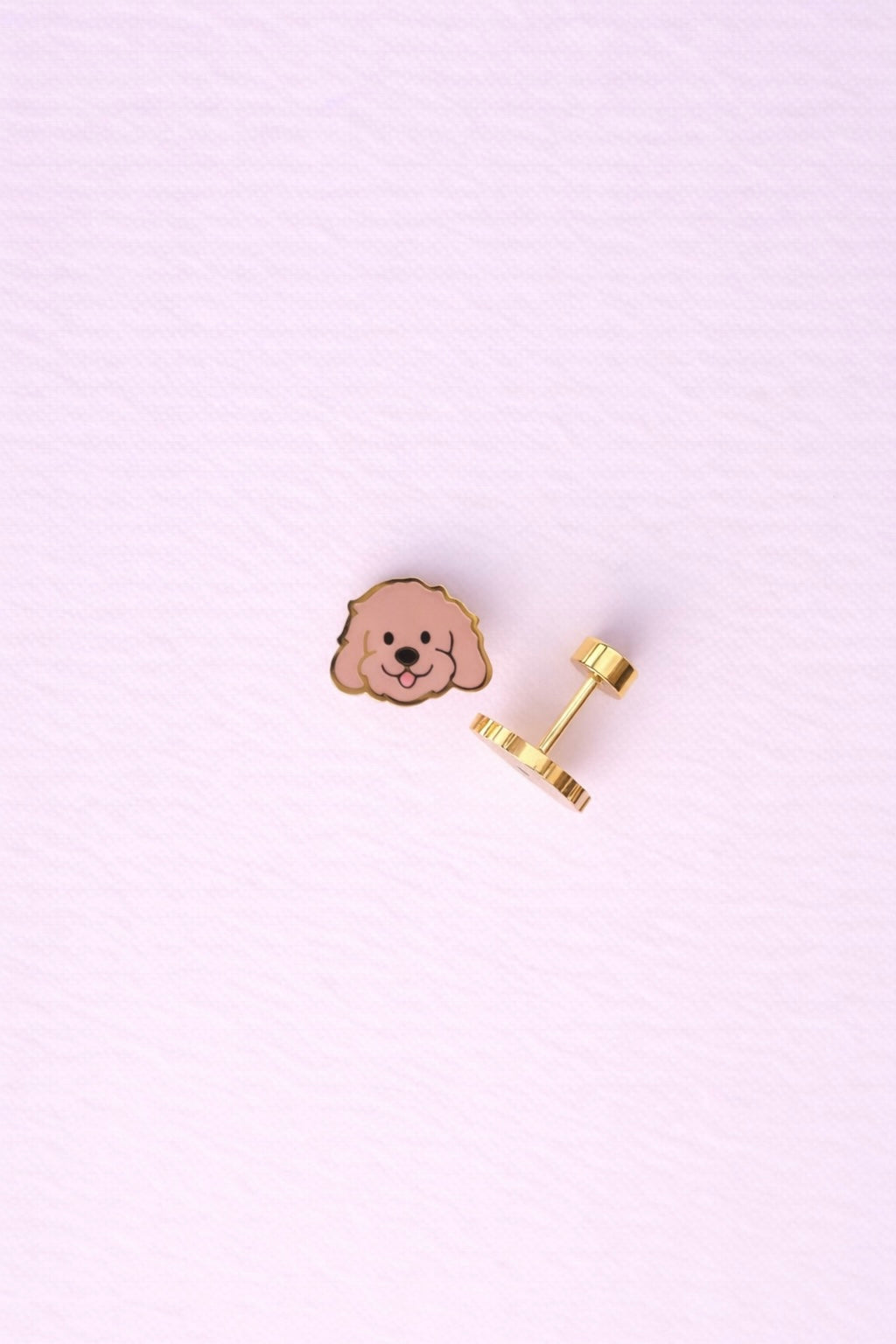Doodle themed screw on flat back stud earrings laying flat and sideways on a light pink background