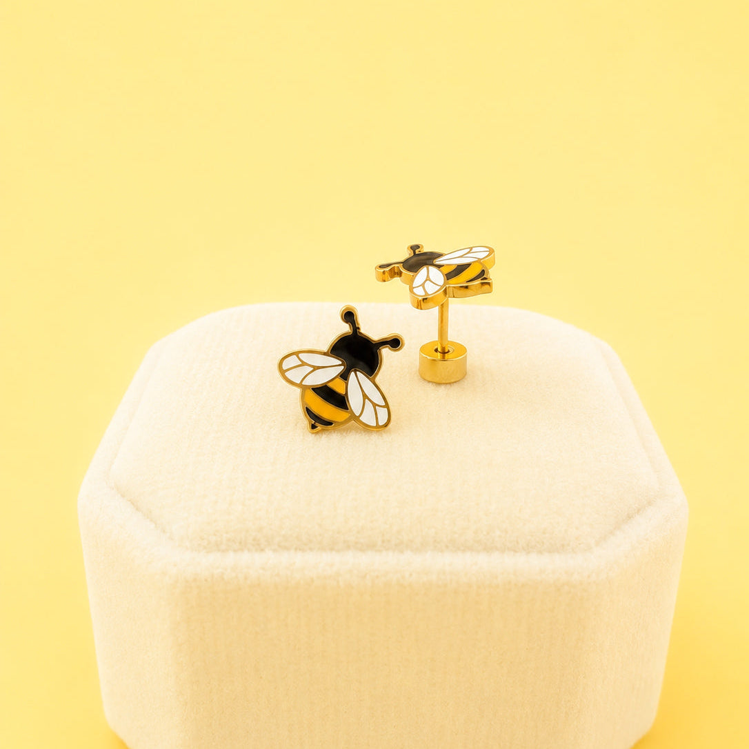 Bee-themed earrings on a white jewelry box with a yellow background