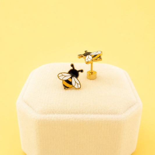 Bee-themed earrings on a white jewelry box with a yellow background