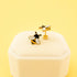 Bee-themed earrings on a white jewelry box with a light yellow background