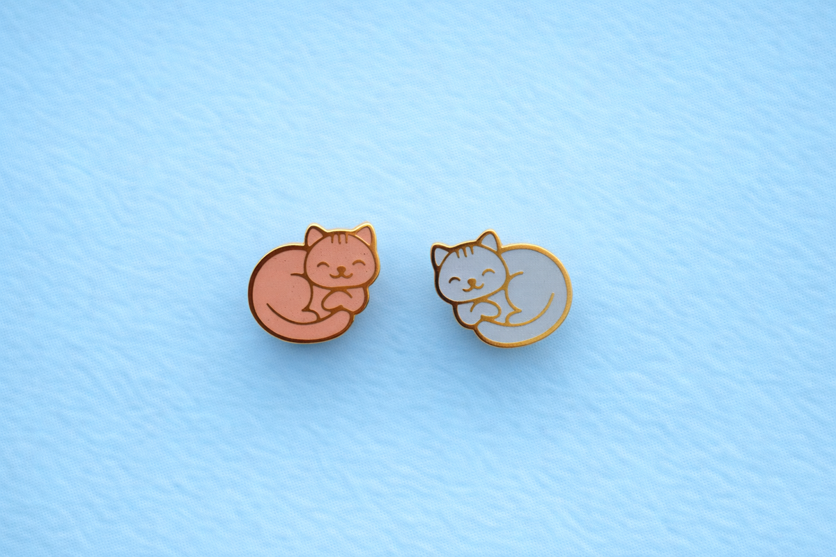 Tabby cat themed flat back earrings with an orange cat and a light blue cat on a light blue background