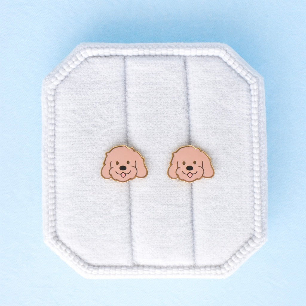 Doodle themed studs on a white jewelry cushion against a light blue background