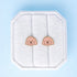 Doodle themed studs on a white jewelry cushion against a light blue background
