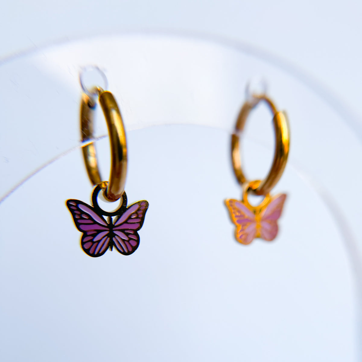 Purple butterfly huggie charms on huggie hoops