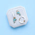 Jewelry set with dolphin-themed charms on white huggies on a hexagonal white stand against a light blue background