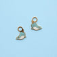 Two blue narwhal-shaped charms on a light blue background