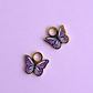 two purple enamel butterfly charms on a light purple background
