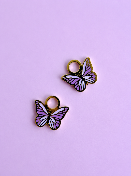 two purple enamel butterfly charms on a light purple background