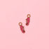 Two pink seahorse-shaped charms on a pink background