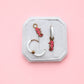 Jewelry set with seahorse charms on a white jewelry box against a pink background