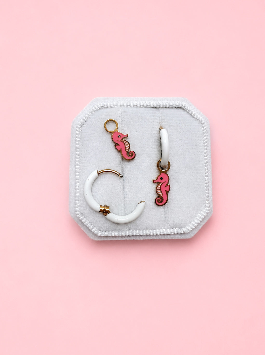 Jewelry set with seahorse charms on a white jewelry box against a pink background