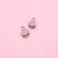 Two pink shell-shaped charms with pearls on a pink background