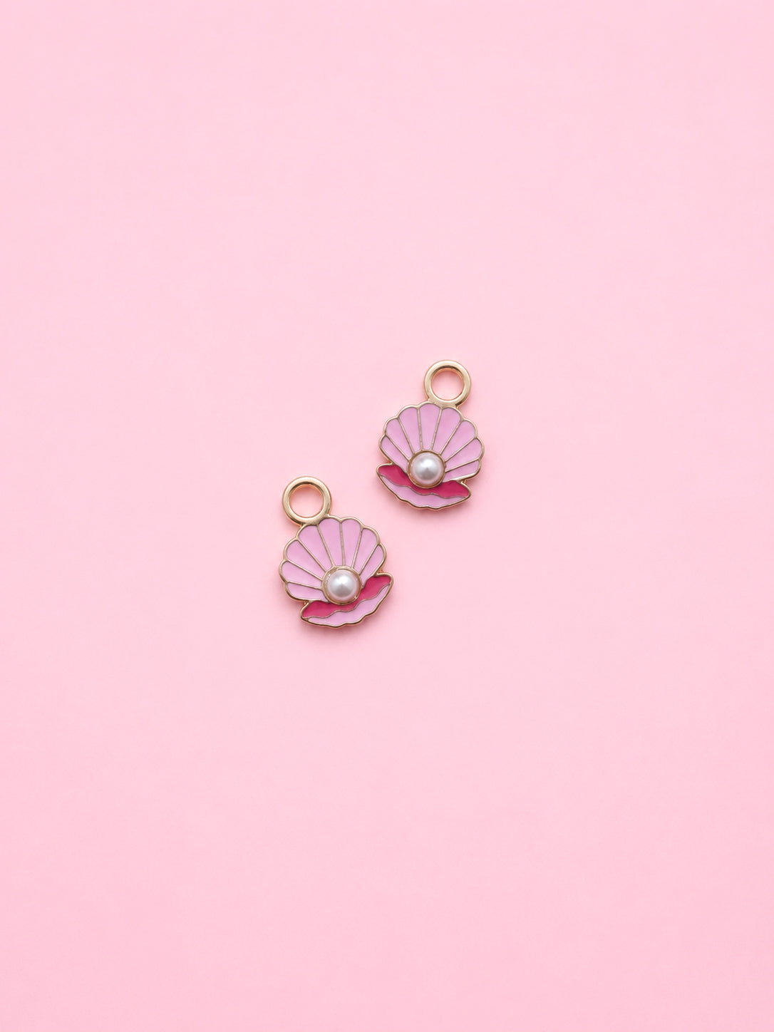 Two pink shell-shaped charms with pearls on a pink background