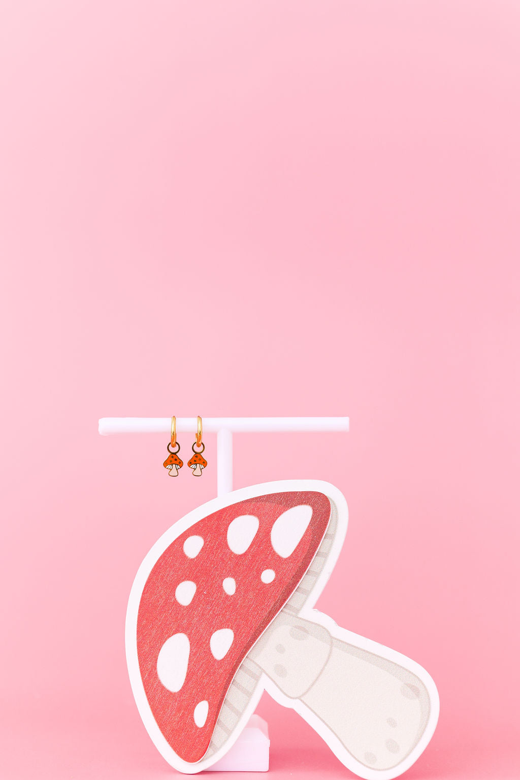 Mushroom-shaped earrings on a pink background