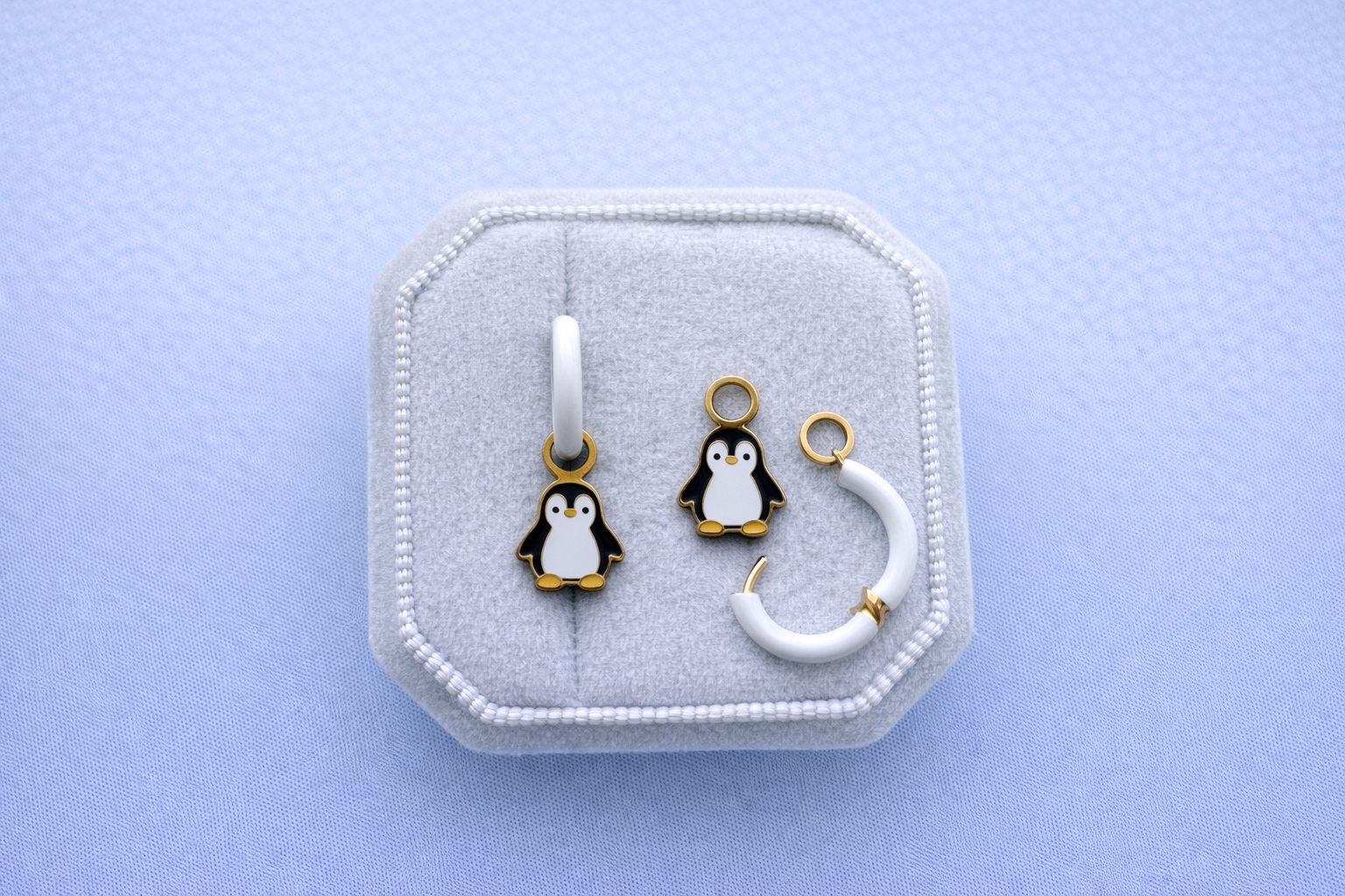 Jewelry set with penguin charms in a white jewelry box on a light blue background
