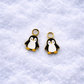 Two penguin charms on a textured white background