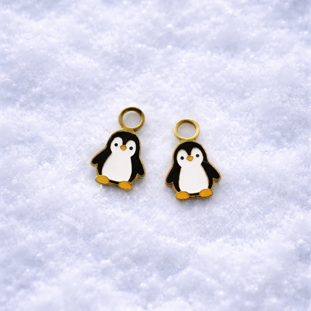 Two penguin charms on a textured white background