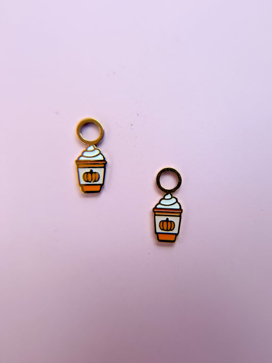 Two pumpkin spice latte-themed charms on a pink background