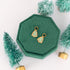 Christmas tree sugar cookie Huggie Charms on a green jewelry box against a white background with mini scrub brush Christmas trees in the background 