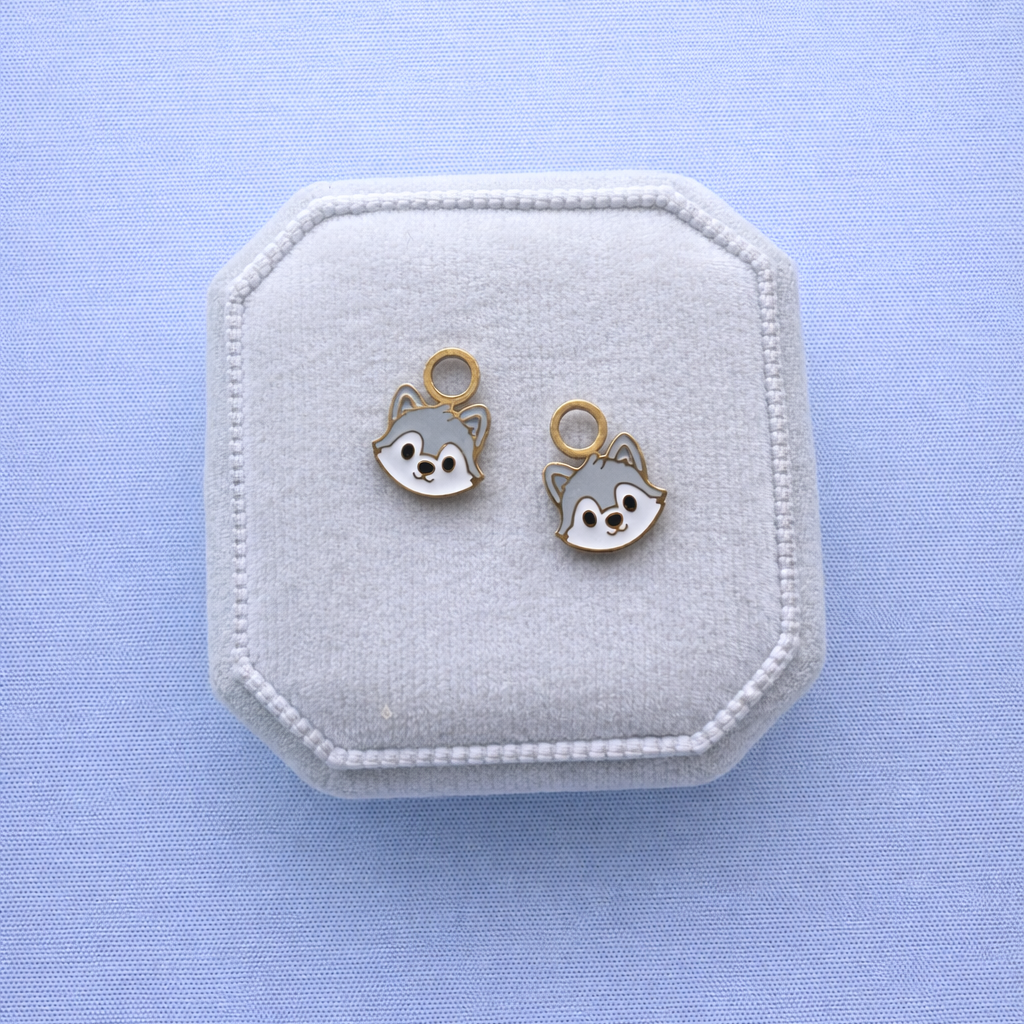 Wolf shaped charms on a white jewelry box against a light blue background