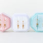 Three hexagonal jewelry display cases with earrings on a white background