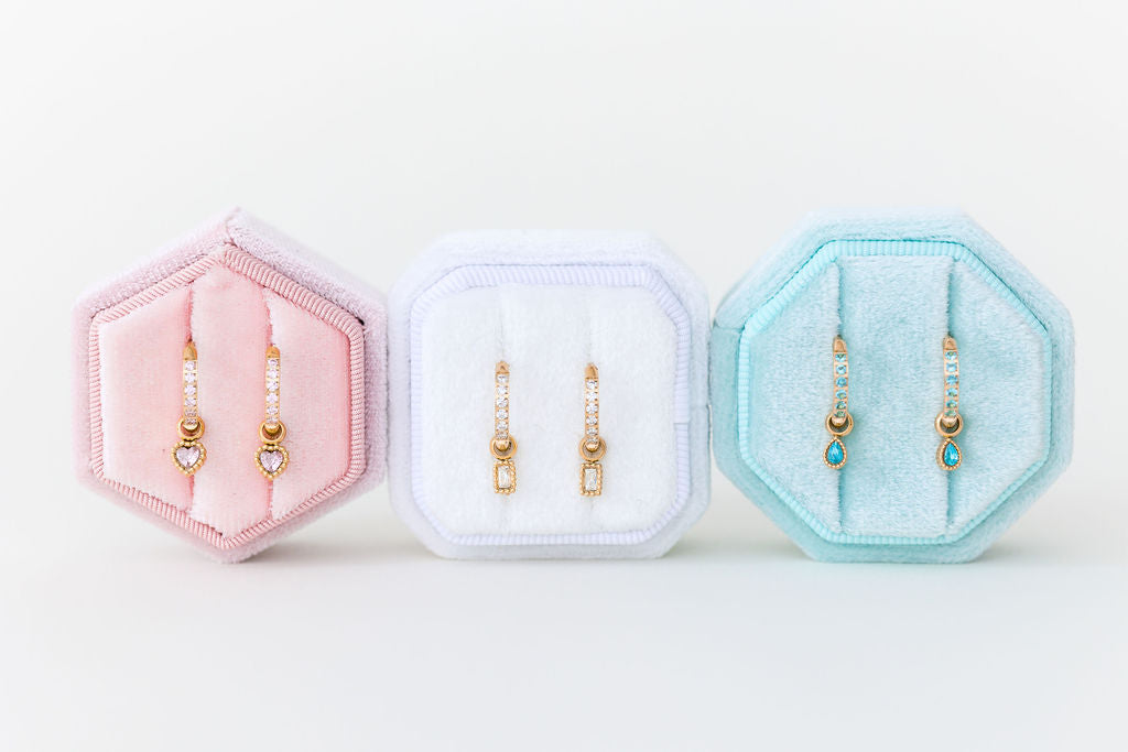 Three hexagonal jewelry display cases with earrings on a white background