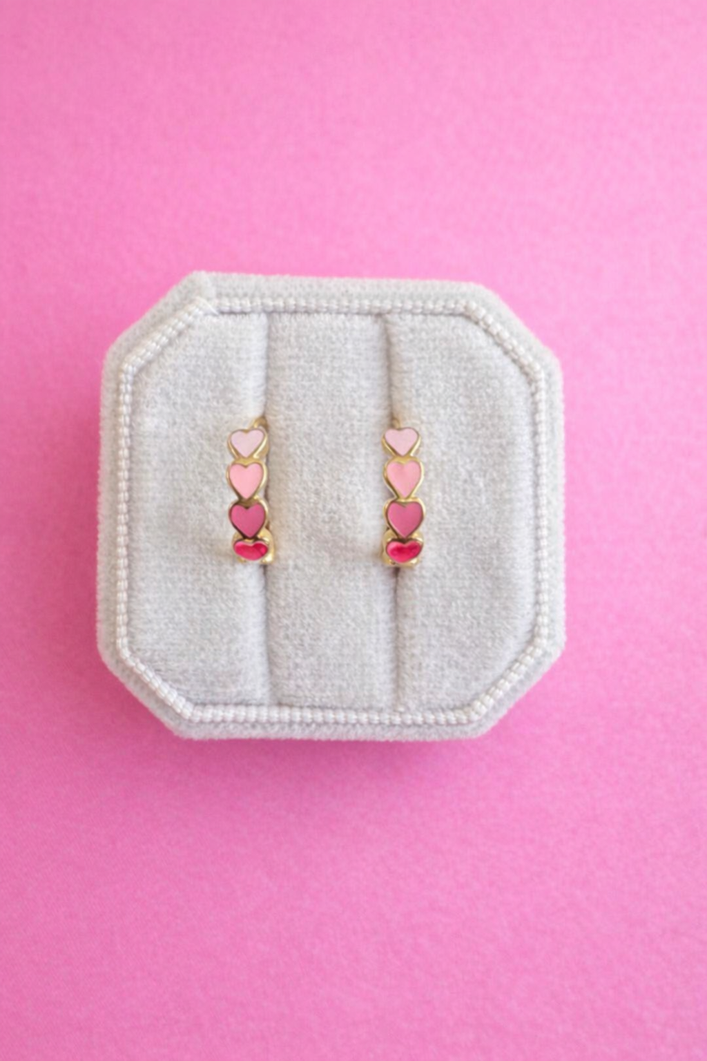 Pink Ombre Heart Chunky Huggie Hoops on a white jewelry box on a pink background