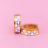 Lavender Checkered Chunky Huggie Hoops on a light pink background