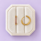 Lavender cz huggie hoops on a white jewelry box on a lavender background