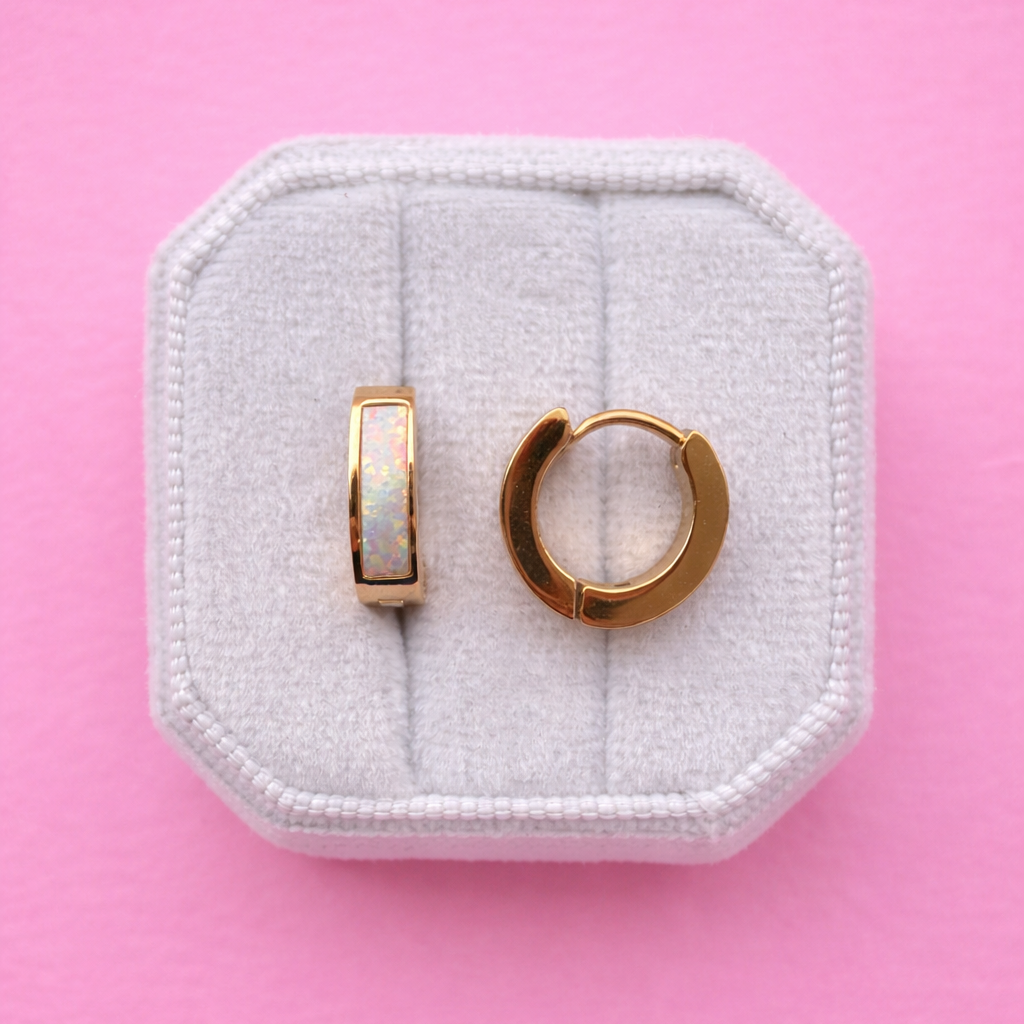 Chunky gold hoops with Opal accents on a white jewelry box against a light pink background