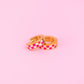 Two checkered earrings on a pink background