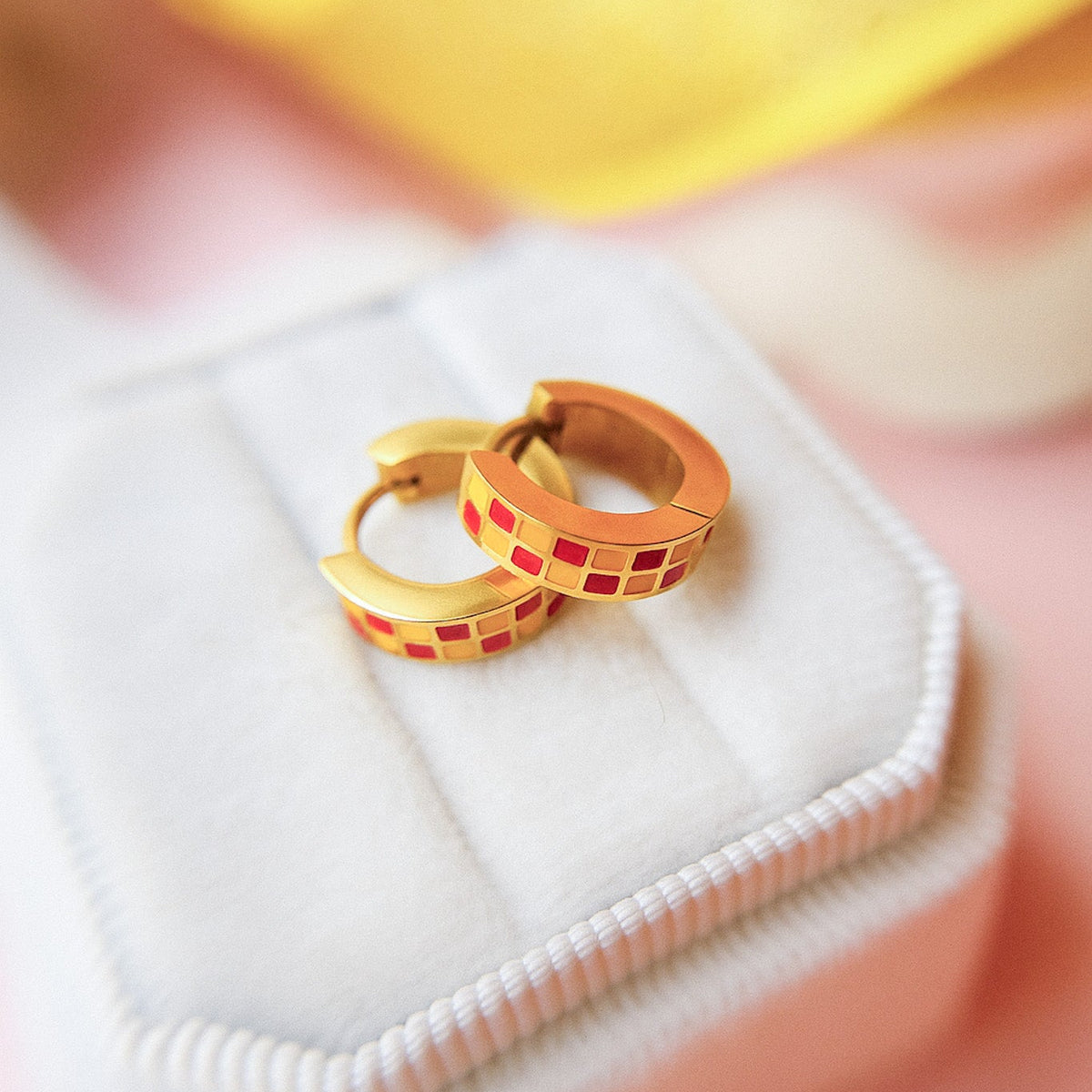 red and yellow checkered huggie hoops on white jewelry box