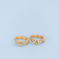 A pair of gold hoop rings with small star-shaped spikes and clear rhinestone accents, displayed on a soft light blue background.