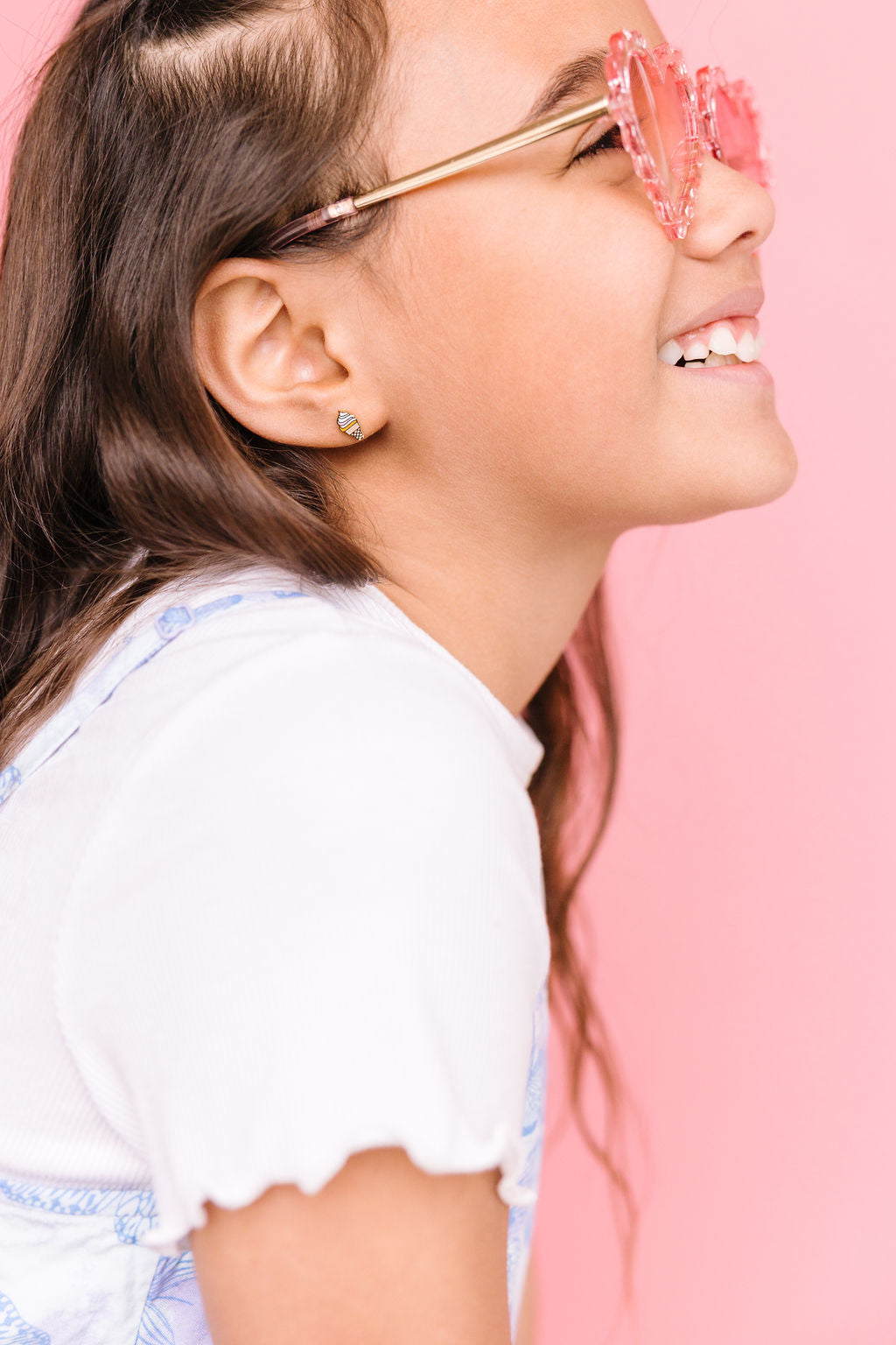 Girl wearing rainbow swirl ice cream cone stud earrings