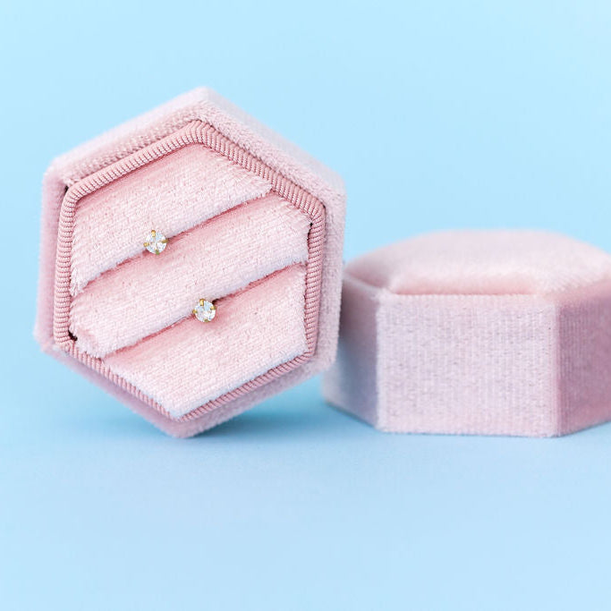 Hexagonal pink jewelry box with an earring on a light blue background
