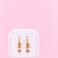 Heart-shaped earrings in a white box on a pink background