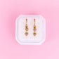 Heart-shaped earrings in a white box on a pink background