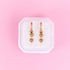Heart-shaped earrings in a white box on a pink background