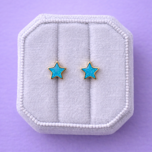 Star-shaped earrings on a white jewelry box against a purple background