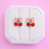 Bow Cherry Stud Earrings on a white jewelry box on a pink background