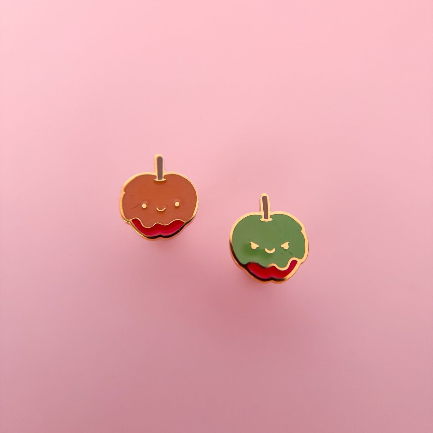 Two candy apple-shaped flat back stud earrings on a pink background