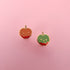 Two candy apple-shaped flat back stud earrings on a pink background