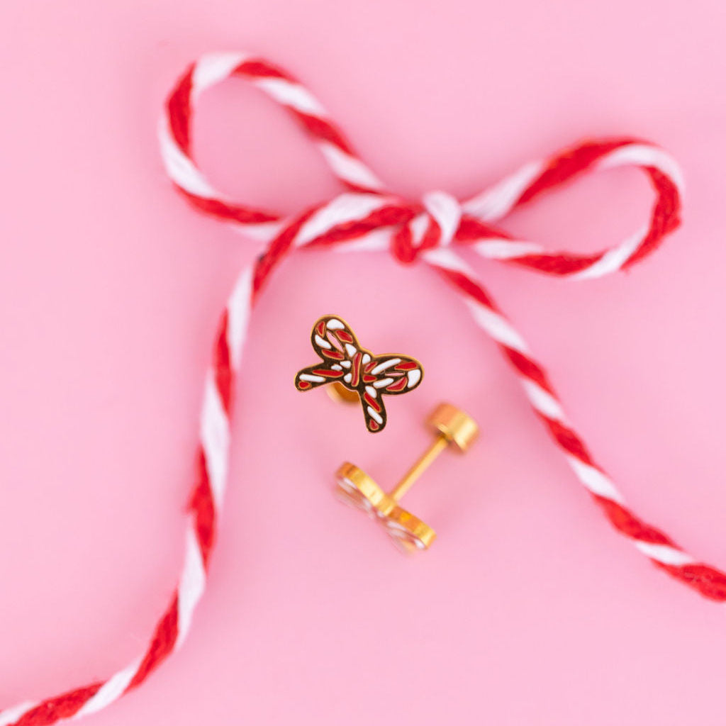 Candy cane bow flat back studs against a light pink background with a candy cane colored string in the shape of a bow